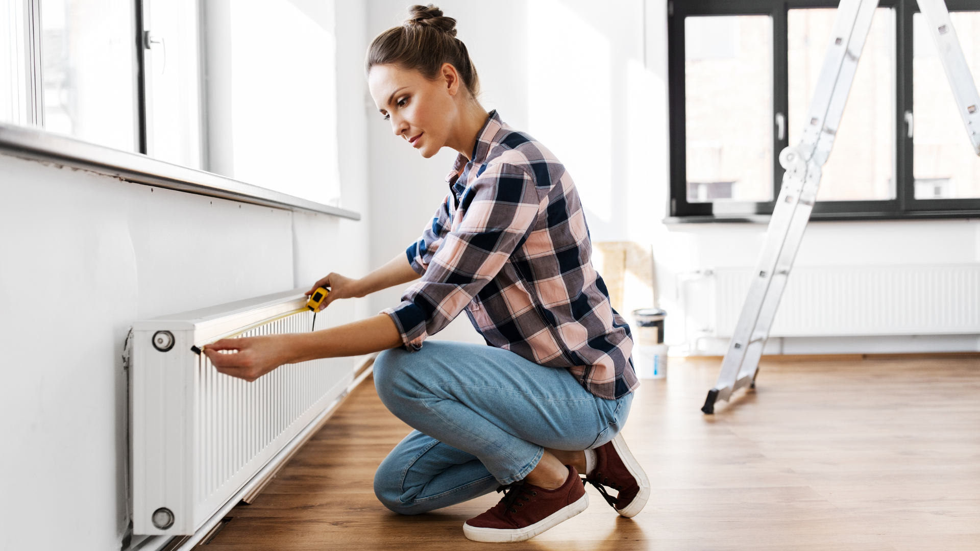 Jeune femme prenant les mesures de son radiateur pour installer une étagère sans perçage